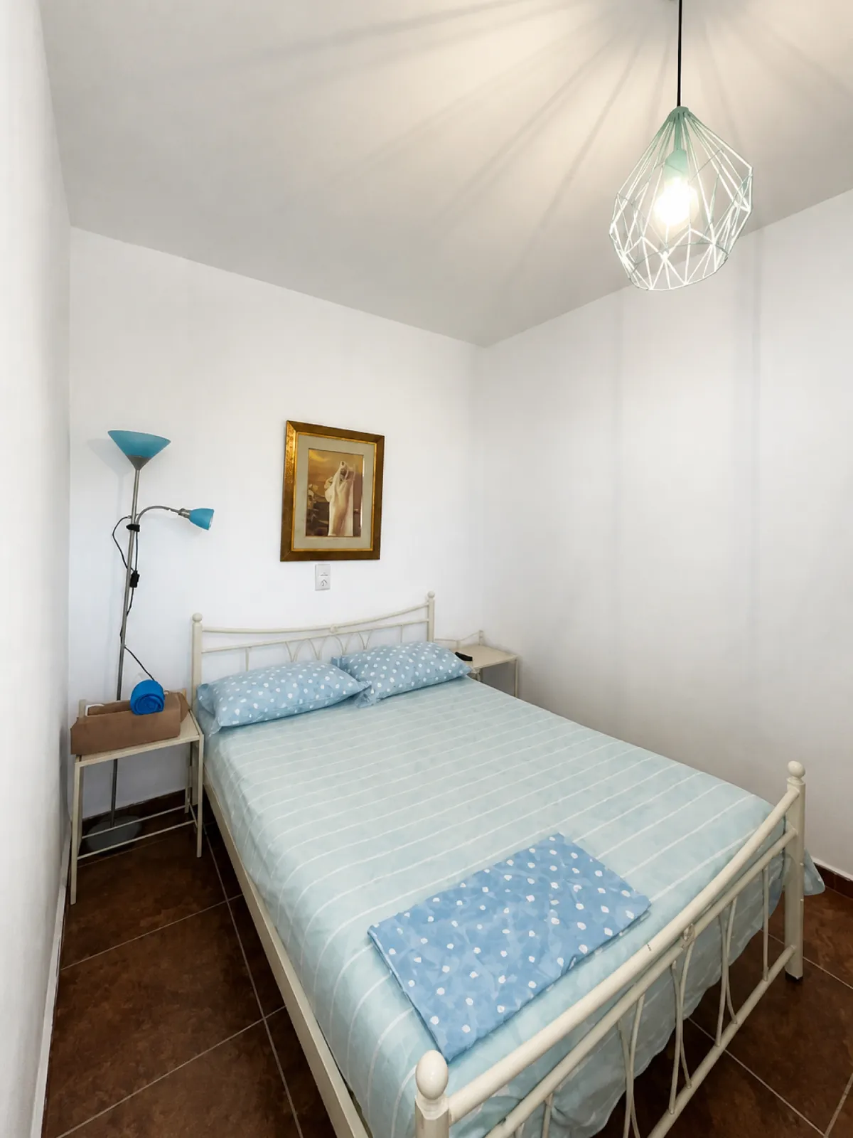 Bedroom in a sea-view apartment with a double bed, pale blue linen and white walls